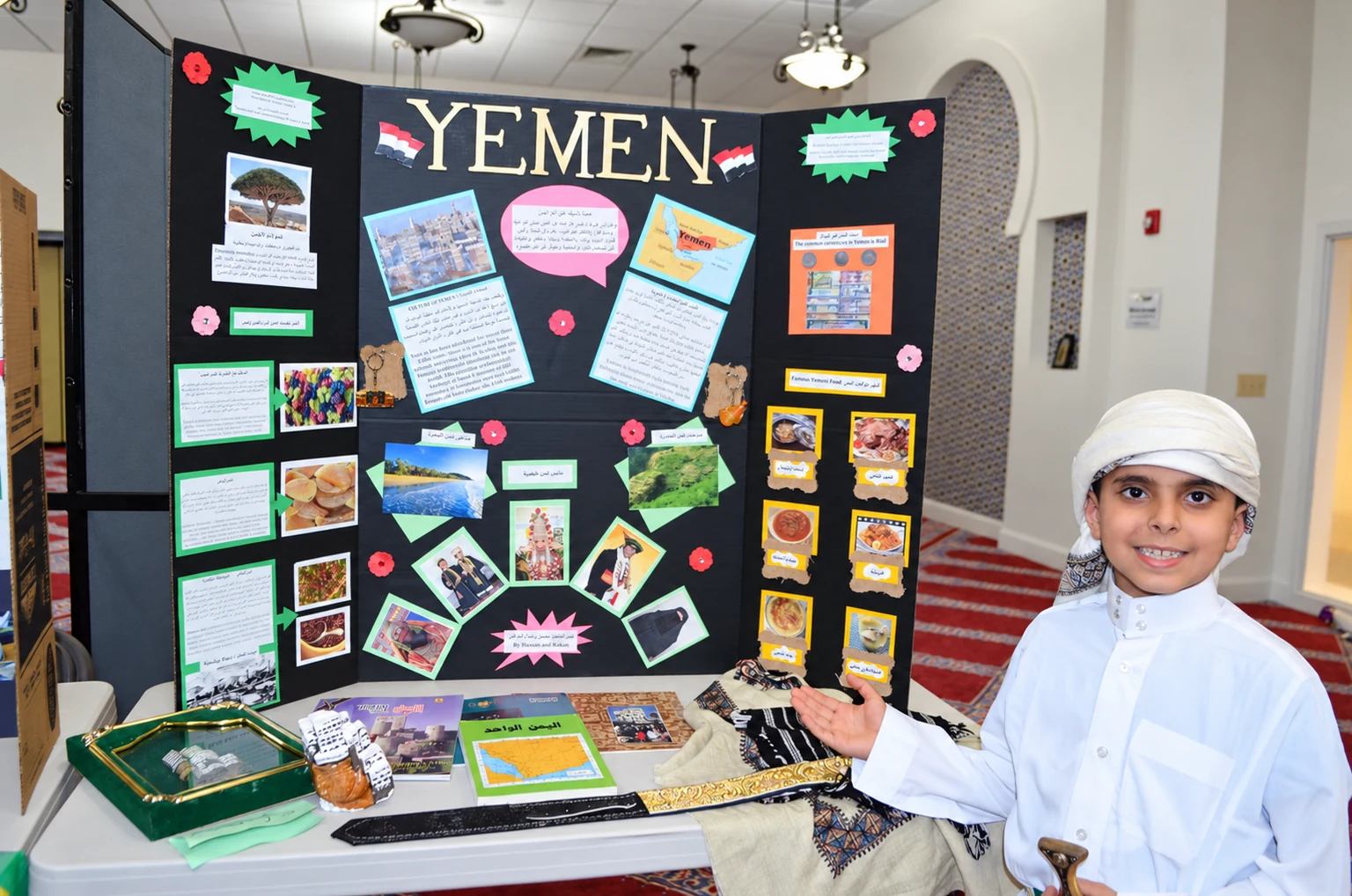 An Al Huda student presenting a school project about Yemen beside his display board.